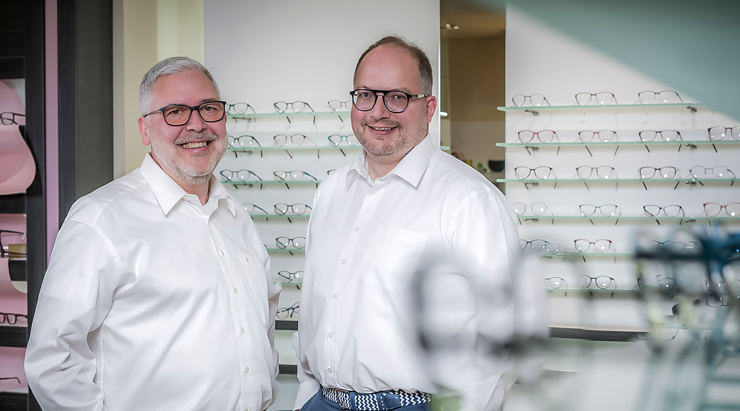 Zwie Geschäftsführer eines Brillengeschäfts vor einem Regal mit Brillen