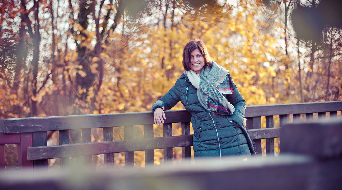 Herbstportrait einer Frau auf einer Holzbrücke