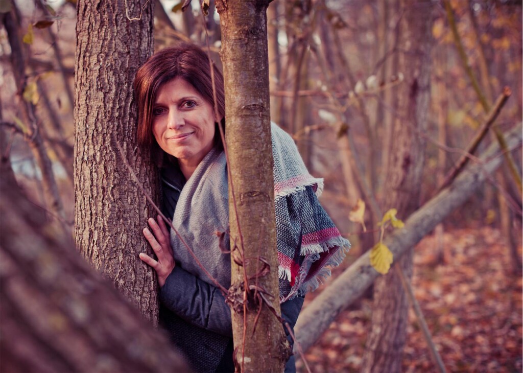 Herbstportrait einer Frau, die sich an einen Baum lehnt