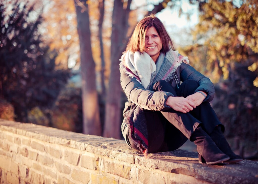 Herbstportrait einer Frau, die auf einer Mauer sitzt