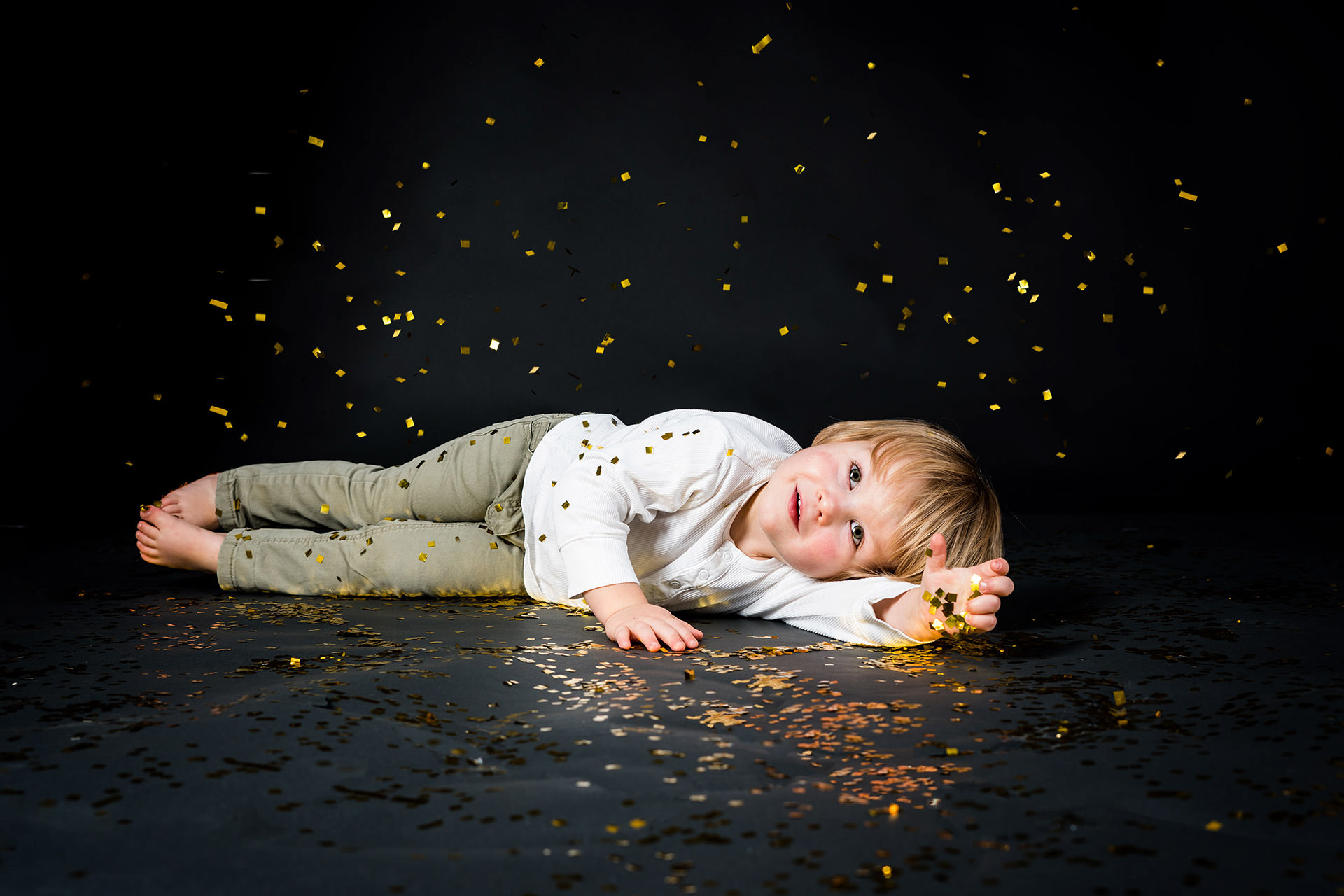 Junge liegt auf dem Boden mit goldenem Glitzerregen