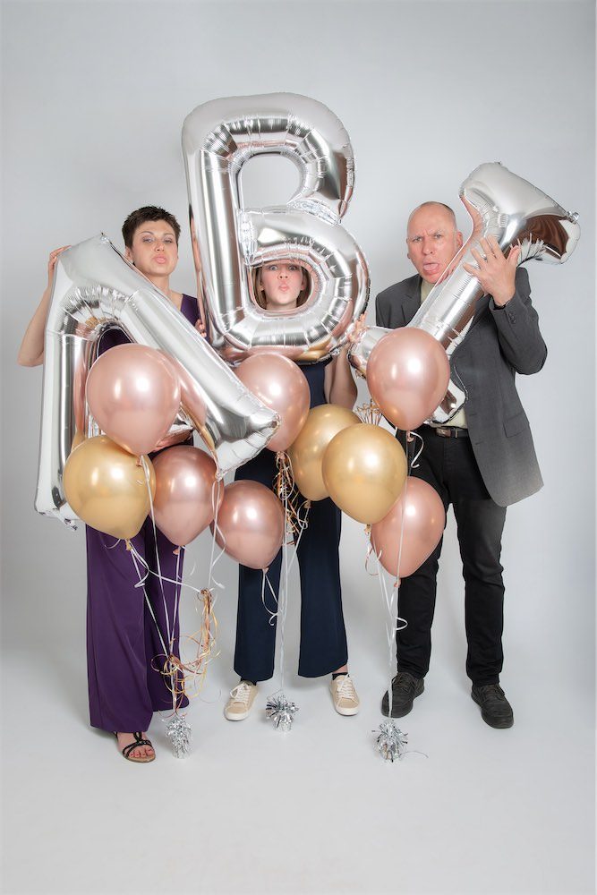 Eltern mit Tochter mit Buchstaben-Luftballons die das Wort ABI bilden