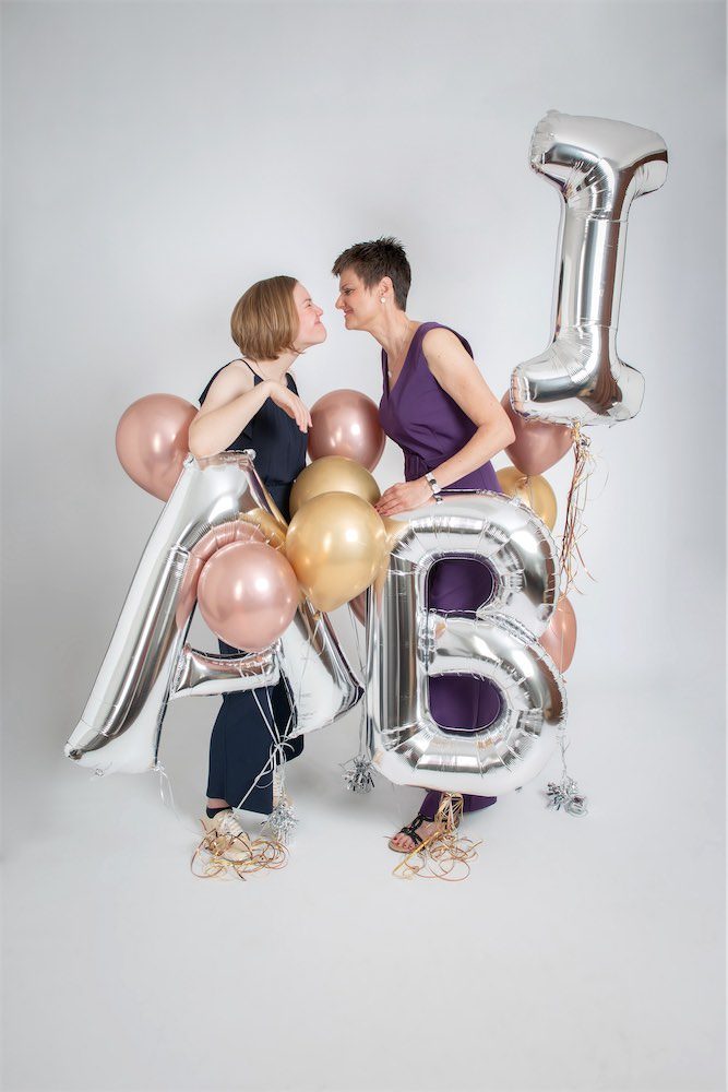 Mutter und Tochter mit Buchstaben-Luftballons die das Wort ABI bilden
