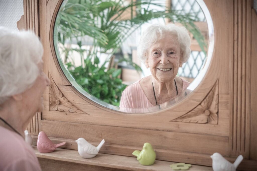 Spiegelbild einer Seniorin in dem Spiegel einer Kommode