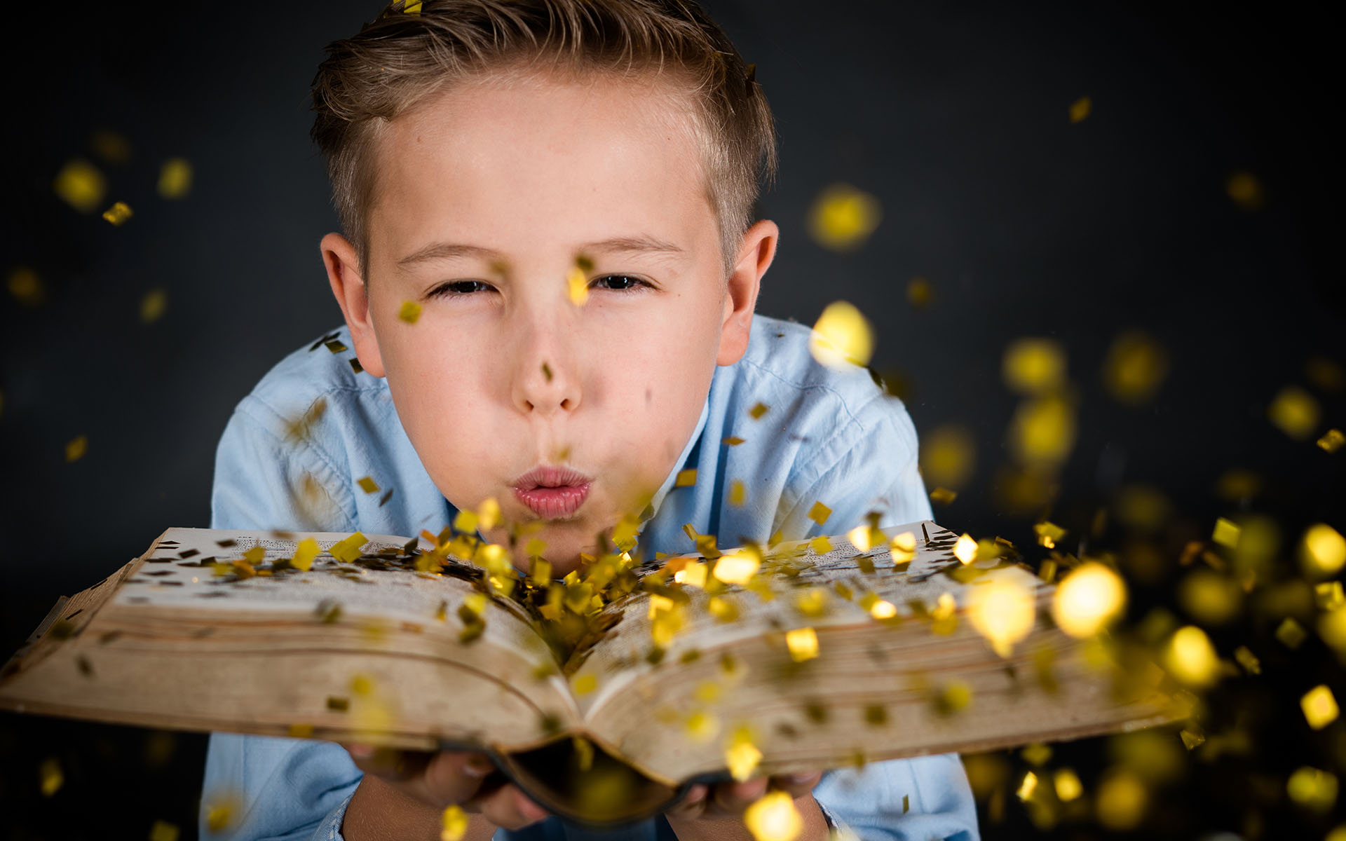 Junge mit Buch, pustet Glitzer